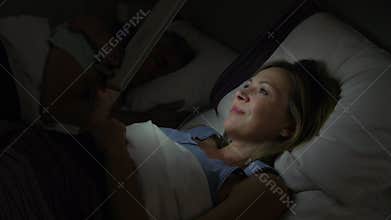 Middle Aged Couple In Bed With Woman Using Tablet Computer