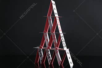 House of playing cards on black mirror surface, closeup