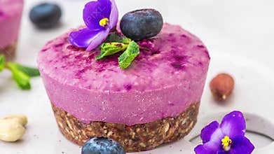 Blueberry and acai vegan cashew cakes with fresh berries, edible flowers, mint, nuts. Healthy vegan food concept. Tasty