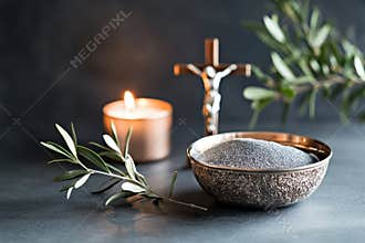 Religion, faith, liturgy, Ash Wednesday, Lent background. Burning candle, brown wooden cross, silver ceremonial ash bowl
