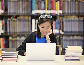 Asian woman in library with laptop