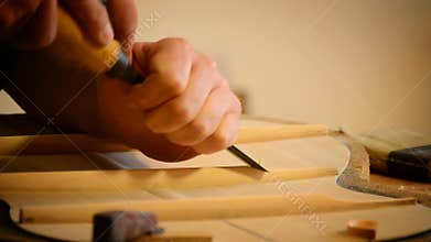 Luthier making a guitar structure with a chisel