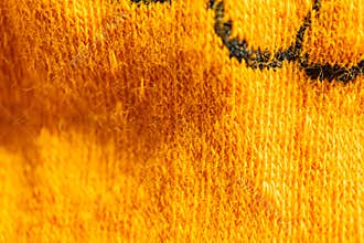 Close-up of a vibrant, textured yellow fabric with a plush weave pattern Possibly part of clothing or home furnishings