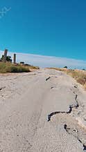 Cracked asphalt road leading to horizon under blue sky