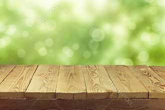 Empty wooden deck table with foliage bokeh background. Ready for product display montage.