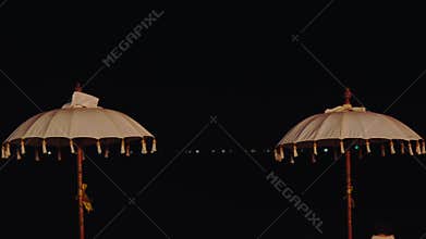 Elegant White Balinese Tedung Umbrellas Against a Dark Sky