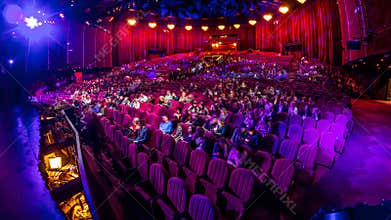 Spectators gather in the auditorium and watch the show in theatre timelapse. Large hall with red armchairs seats