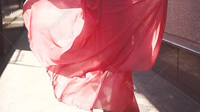 The girl in the red dress walking down the street in the setting sun. the view from the back. slow motion