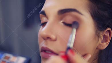 Professional make-up artist applying eyeshadow to model eye using special brush. Beauty, makeup and fashion concept