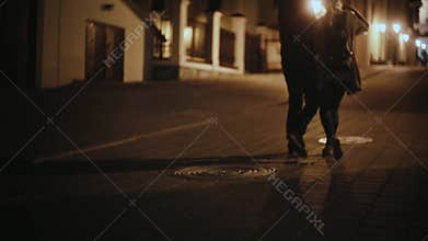 Back view of stylish couple walking in the city centre in the evening together. Man and woman on romantic date.