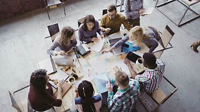 Teamwork in boardroom at modern office. Female team leader giving direction to multiethnic group of people. Top view.