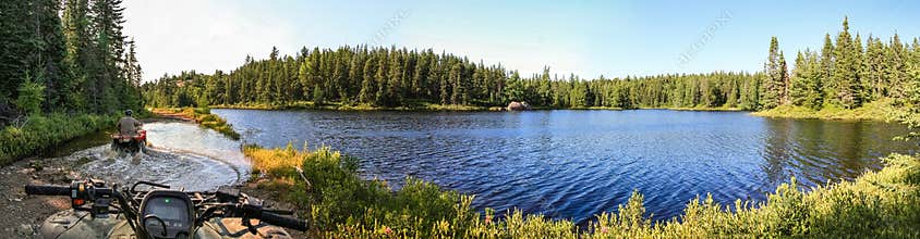 People driving ATV quads through water. Lake in Ontario, Canada.