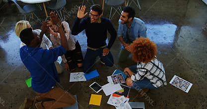 Team of executives giving high five to each other in the meeting
