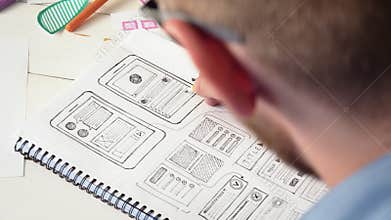 UX designer sketching prototype of a new app in his notebook