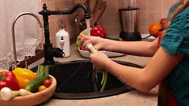 Young girl hands washing vegetables at the kitchen sink