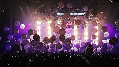 Many balloons falls on people in the concert hall