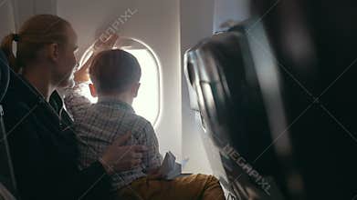 Boy and mother looking outside through plane