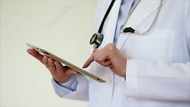 Stethoscope with doctor using tablet PC in medical clinic