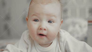 Cute Little Baby is Looking into the Camera and is Happy on a bed. Baby Smiles and Laughs.