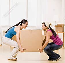 Women moving into new home and carrying box