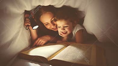 Family reading bedtime. Mom and child reading book with a flashlight under blanket