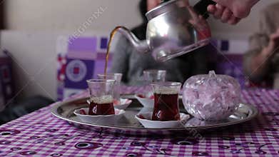 Close-up of a man's hand pours tea from the kettle black tea in bowl
