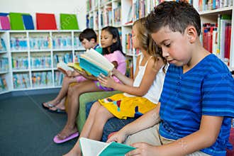 Students reading books while sitting on seats at school library
