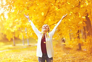 Leaf fall, happy expression young woman having fun in warm sunny autumn