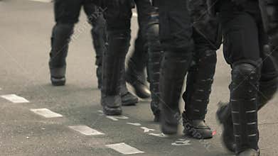 Riot police walking on road.
