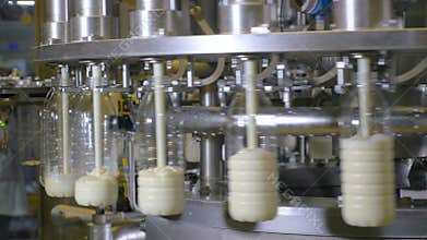 Milk pouring into plastic bottles at a food factory. Close up.