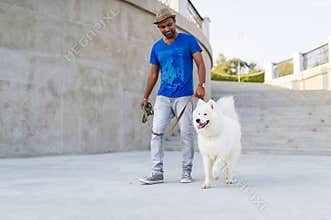 Happy asian man with samoyed dog walking in summer city park.