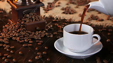Black hot coffee poured into white cup from coffee pot
