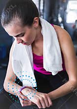 Fit woman using fitness band in gym against spiral dots in background