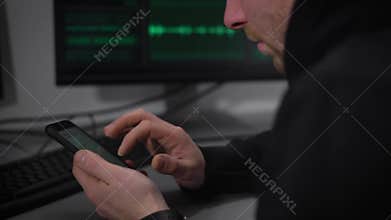 Young but experienced IT expert sets up your smartphone to work with complex programs in banking fraud. Man in a dark