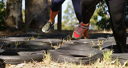 Low section of women running over tyres during obstacle course