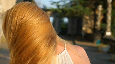 Beautiful woman styling hair outdoors. Super Slow Motion. Happy calm girl with long hair, having fun in the park