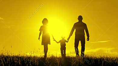 Happy family walking, holding hands at sunset.