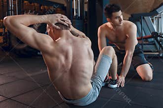 Fit mens doing sit-ups on exercise mats at fitness club