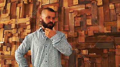 Man with beard thinking near wall.
