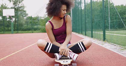 Charming model sitting on skateboard
