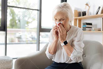 Unhappy elderly woman sneezing
