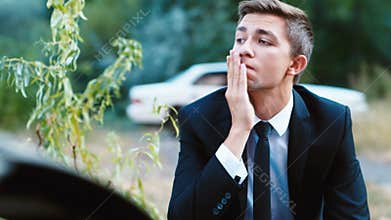 The young driver from the car burned. Calls insurance agent. Concept: accident, fire, auto