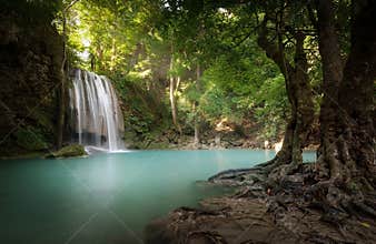 Waterfall ans sunlight beams and rays shine through leaves