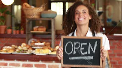 Smiling barista holding an open signboard