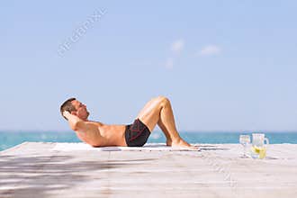 Young fit man doing abs crunches exercise outdoors