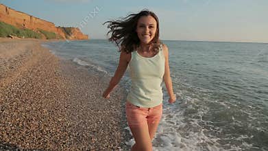 Happy girl running along the beach barefoot and