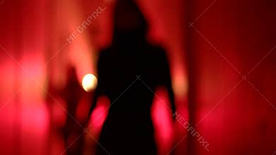 Silhouette of two women in high heels dancing in a blurry, red corridor