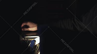 Male hand of hacker in hood typing crack code using computers in dark room