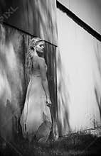 Beautiful blonde woman in feminine dress outside a rustic building