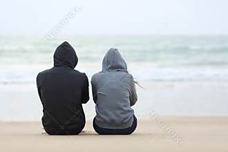 Two sad teenagers sitting on the beach